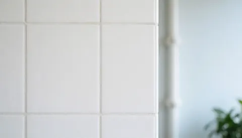 Mur recouvert de carreaux céramiques blancs avec des joints gris clair, offrant une surface lisse et uniforme idéale pour superposer du texte ou servir de décor neutre.