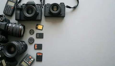 Matériel de prise de vue professionnelle incluant appareils photo et objectifs disposés sur une surface grise unie.