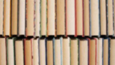Arrière-plan composé de livres empilés sur une étagère avec des dos multicolores, idéal pour un design web ou éditorial.