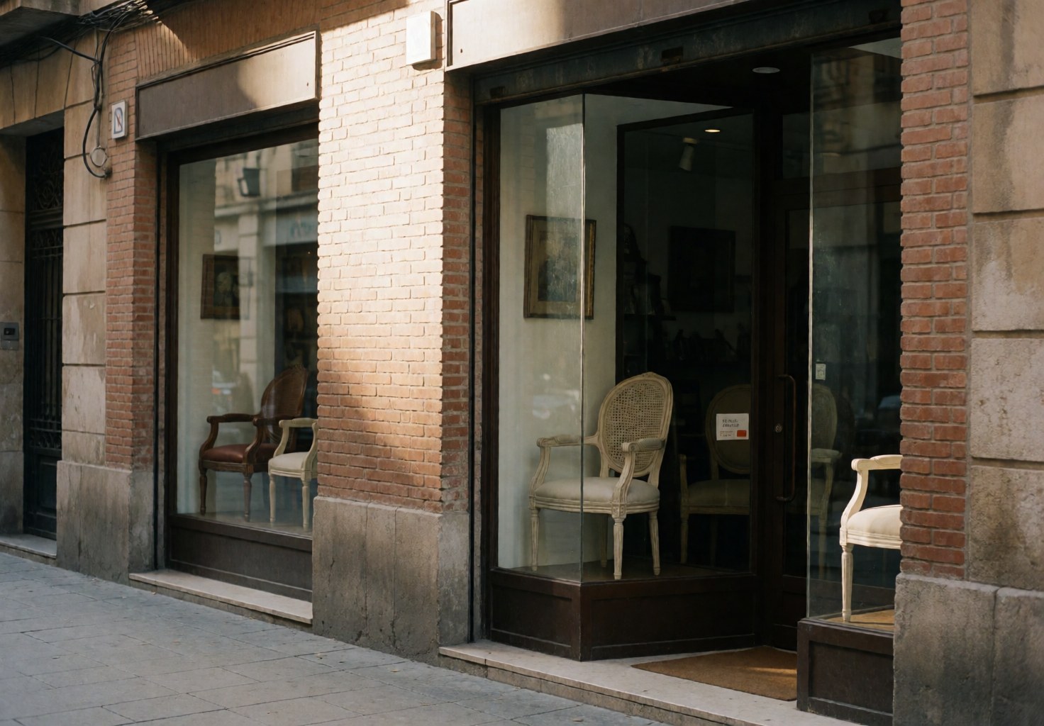 Façade d'une boutique de meubles avec des vitrines en verre exposant des chaises et des meubles classiques sur une rue.