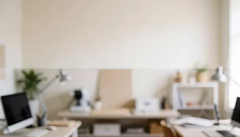 Vue d'ensemble d'un espace de travail avec des bureaux, des ordinateurs et des lampes sur fond flou.