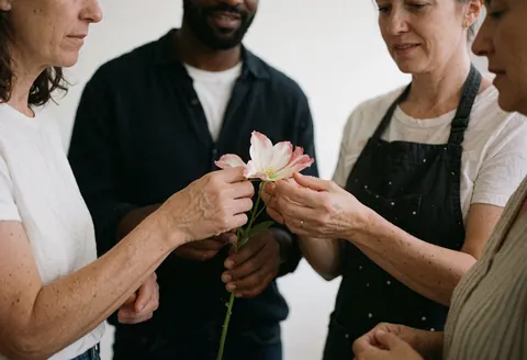 Une fleuriste et une cliente collaborent sur un arrangement floral pendant que d'autres observent attentivement.
