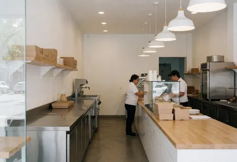 Vue intérieure d'un restaurant de tacos avec un comptoir, une cuisinière, un réfrigérateur et des murs blancs.