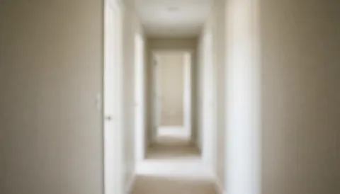 Vue d'un couloir intérieur épuré aux murs blancs et à une porte beige, servant de fond neutre pour textes ou présentations professionnelles.