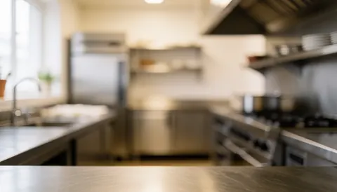 Surface en acier inoxydable d'une cuisine commerciale avec éclairage chaud, idéale pour superposer du texte ou des graphiques dans un contexte professionnel.