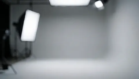 Fond studio professionnel avec éclairage diffus et murs gris, idéal pour portraits corporatifs et textes commerciaux.