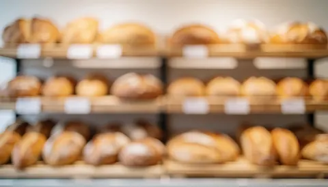 Arrière-plan doux et chaleureux d'une boulangerie montrant des étagères remplies de différents types de pain, idéal pour ajouter du texte.