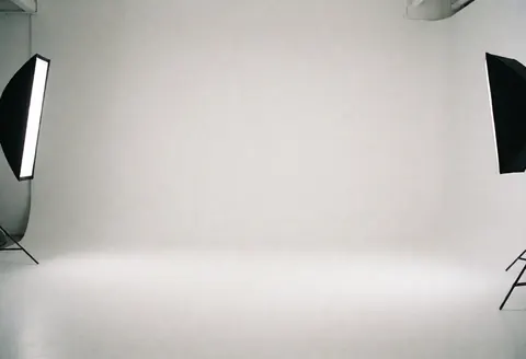 Studio professionnel aux murs blancs équipé d'éclairages softbox, idéal pour des portraits corporatifs et de la photographie d'entreprise.