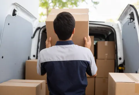 Un employé de logistique charge des marchandises dans un véhicule utilitaire, illustrant le service de livraison en action pour les entrepreneurs.