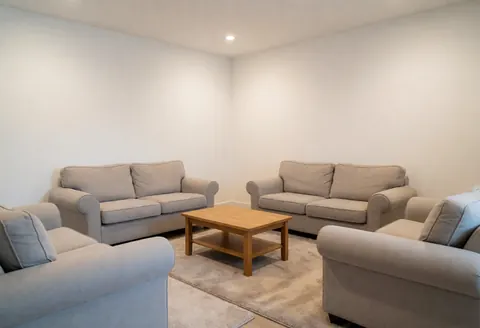 Intérieur d'un cabinet de psychologie avec un canapé confortable, une table basse en bois, un mur blanc et une lumière douce créant une ambiance sereine.