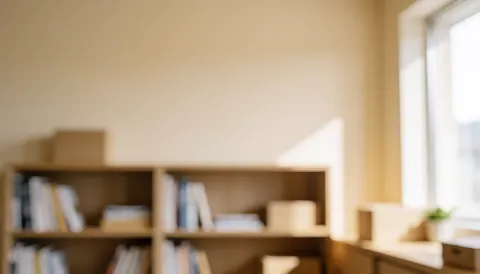 Arrière-plan flou d'un bureau moderne avec étagère en bois, mur beige et lumière naturelle par la fenêtre, idéal pour textes et marketing services psychologie bien-être.