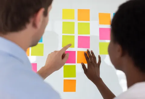 Des notes adhésives colorées collées sur un mur pour organiser une réunion d'équipe en bureau.