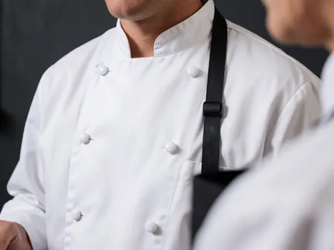 Gros plan sur la texture du tissu gris d'une veste de travail, mettant en évidence les boutons, la couture résistante et le col pour un uniforme professionnel durable.