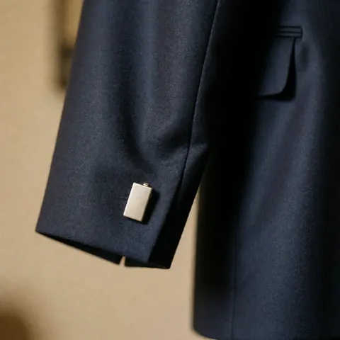 Gros plan sur les détails d'un costume bleu marine : col, bouton de manchette, texture du tissu et coupe élégante pour un usage commercial.