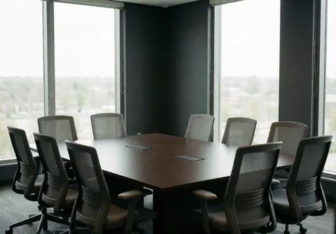 Salle de réunion contemporaine dotée d'une table en bois sombre et de chaises ergonomiques, agrémentée de grandes fenêtres offrant une vue extérieure et de murs gris anthracite.