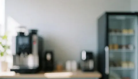 Arrière-plan lumineux et flou d'une salle de pause moderne avec une machine à café et un réfrigérateur, idéal pour ajouter du texte.