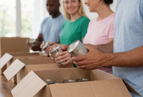 Bénévoles triant des boîtes et des conserves pour la communauté lors d'une collecte de dons.
