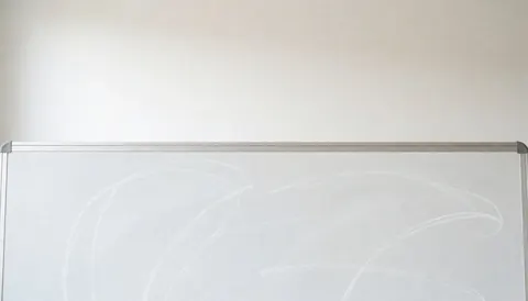 Fond blanc avec tableau noir et traces de craie, idéal pour textes éducatifs. Scène propre, minimaliste et réaliste pour usage universitaire ou en classe.