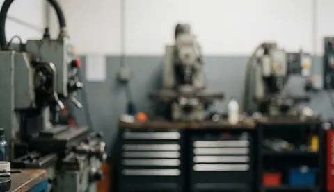 Fond gris neutre et flou représentant un environnement de fabrication industrielle avec des équipements métalliques pour texte ou design.