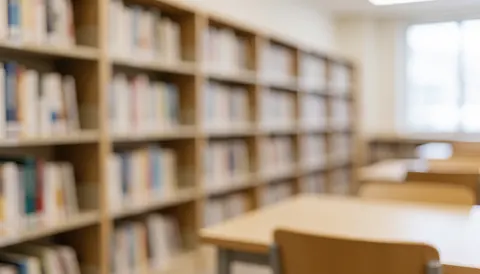 Arrière-plan flou montrant des étagères remplies de livres et des tables dans un environnement calme propice à l'étude universitaire.