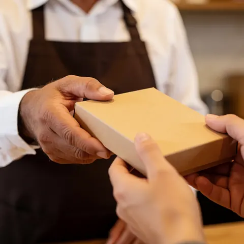 Remise d'une boîte contenant du café et du cacao entre le vendeur et le client