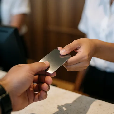 Prise de vue rapprochée d'une main remettant une clé métallique à une autre main lors de l'enregistrement à l'hôtel.