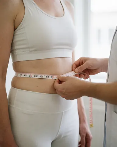 Un nutritionniste mesure la taille d'un client avec un mètre ruban lors d'une consultation pour le suivi de la santé.