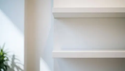 Une étagère murale blanche au design épuré et moderne, offrant un fond vide et lumineux idéal pour la mise en page de textes ou la présentation de produits technologiques.