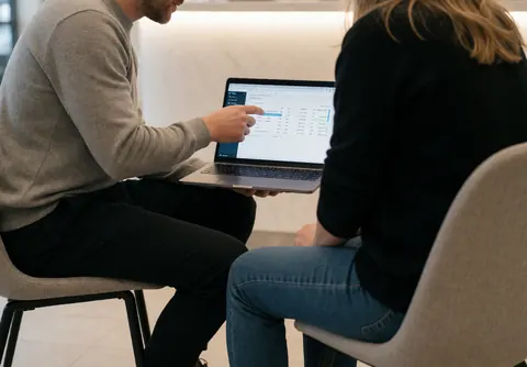 Un expert en marketing présente des analyses à un client dans une réception moderne et bien éclairée.