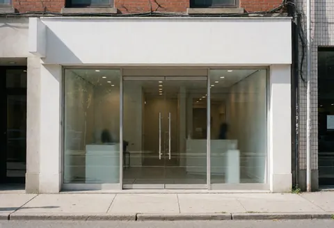 Façade d'un cabinet de conseil moderne avec portes en verre, intérieur propre et professionnel, idéal pour les ressources humaines, éclairage naturel du jour.
