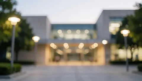 Façade contemporaine d'un campus universitaire baignée par la lumière dorée du soir avec un effet de flou artistique en arrière-plan.