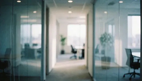 Couloir de bureau contemporain aux parois vitrées, mobilier flou, éclairage doux et tons bleus blancs, fond neutre idéal pour textes professionnels.