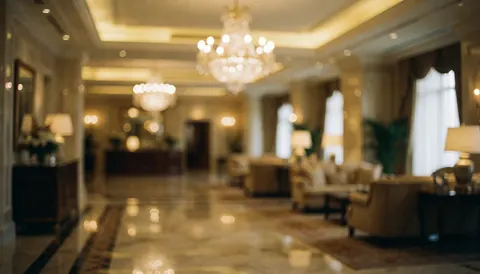Hall d'hôtel élégant au sol en marbre, illuminé par des lustres et des lumières chaudes, meublé de canapés confortables pour un fond professionnel.