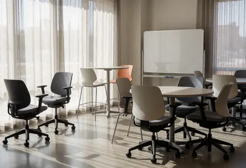 Salle d'étude universitaire moderne avec chaises ergonomiques, tables rondes et tableau blanc. Lumière naturelle par les fenêtres.