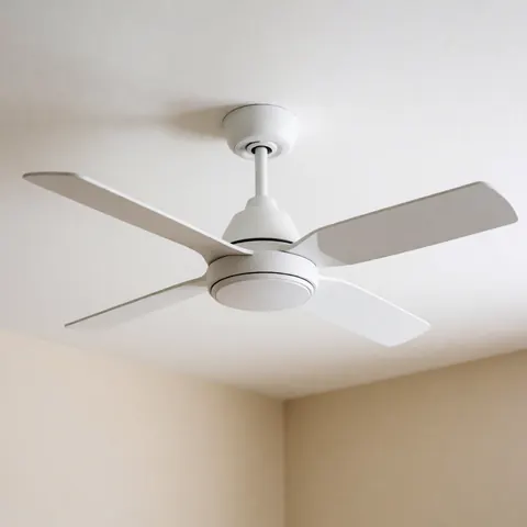 Vue en contre-plongée d'un ventilateur de plafond moderne et minimaliste installé sur un plafond blanc dans une pièce aux murs beige, éclairée naturellement.