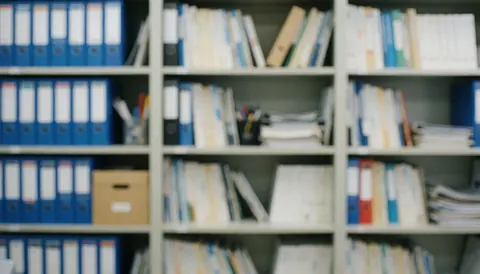 Étagères de bureau remplies de classeurs bleus et de documents, dans des tons bleus et beiges, servant de fond pour textes et présentations professionnelles.