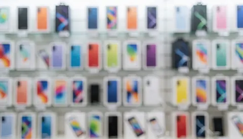 Fond de magasin avec des boîtes de téléphones défocusées, effet bokeh aux couleurs vives, idéal pour textes promotionnels sur sites web ou réseaux sociaux.