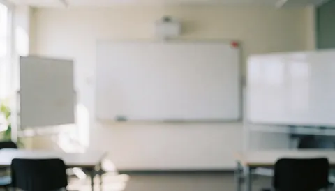 Intérieur d'une salle de classe lumineuse et calme, équipée de tableaux, de tables et de chaises sur un fond neutre adapté aux textes.