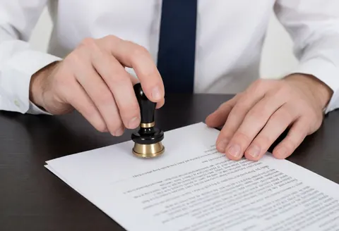 Mains d'un avocat apposant un sceau sur un document légal sur un bureau sombre, action précise et professionnelle, éclairage clair et réaliste.