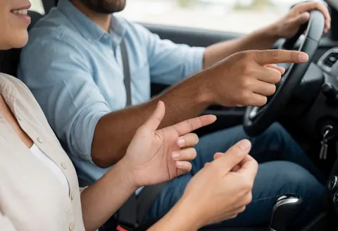 Instructeur guidant un élève lors d'une leçon de conduite à l'intérieur de la voiture sur une route en journée.