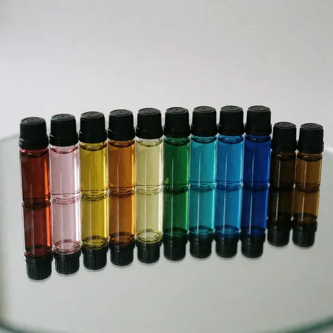Flacons colorés alignés sur un miroir avec reflets nets et éclairage professionnel pour produits spa et bien-être.