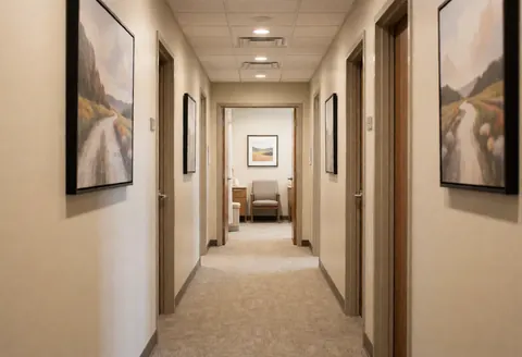 Couloir calme d'un spa présentant des tableaux aux murs, des chaises d'attente et des portes menant aux salles de traitement, dans une ambiance professionnelle.
