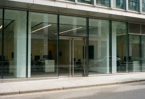 Vue de l'entrée principale d'un immeuble de bureaux contemporain dédié à la technologie, présentant des façades en verre et une architecture urbaine professionnelle.