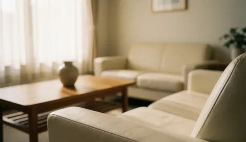 Vue intérieure d'un espace de consultation apaisant comprenant un canapé, une table basse, une fenêtre avec rideaux et une plante, offrant un fond neutre et professionnel pour du texte.