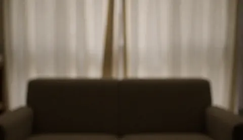 Vue d'un intérieur apaisant pour cabinet psychologique, comprenant un canapé confortable, des rideaux doux et une lumière tamisée créant une ambiance calme.