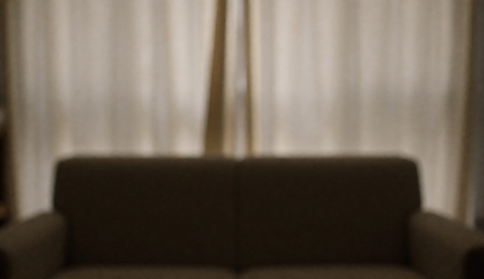 Vue d'un intérieur apaisant pour cabinet psychologique, comprenant un canapé confortable, des rideaux doux et une lumière tamisée créant une ambiance calme.