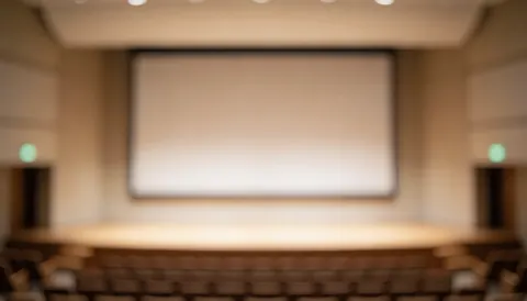 Arrière-plan flou d'un auditorium professionnel avec grand écran et sièges, idéal pour textes et présentations corporatives.