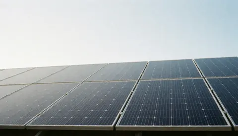 Installation de panneaux photovoltaïques sur une toiture avec beaucoup d'espace vide dans le ciel pour ajouter du texte, idéal comme arrière-plan professionnel.