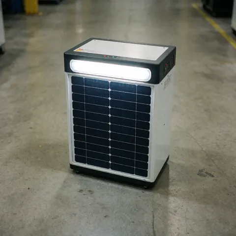 Unité solaire portable avec panneau photovoltaïque et lumière LED sur sol en béton dans un atelier industriel.