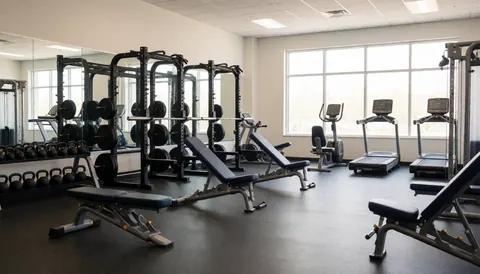 Vue d'une salle de fitness moderne avec des équipements de musculation et des tapis de course dans un espace bien éclairé.